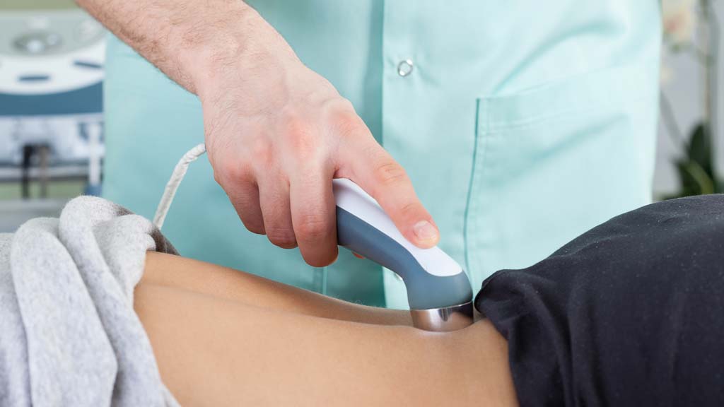 therapist is applying a cold laser to a patients back to relief inflammation and pain