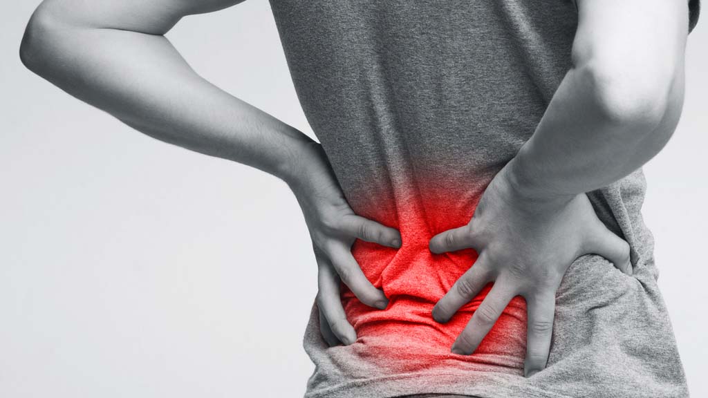patient holding lower back needing pain relief in Stamford, CT. Pain area is shown in red